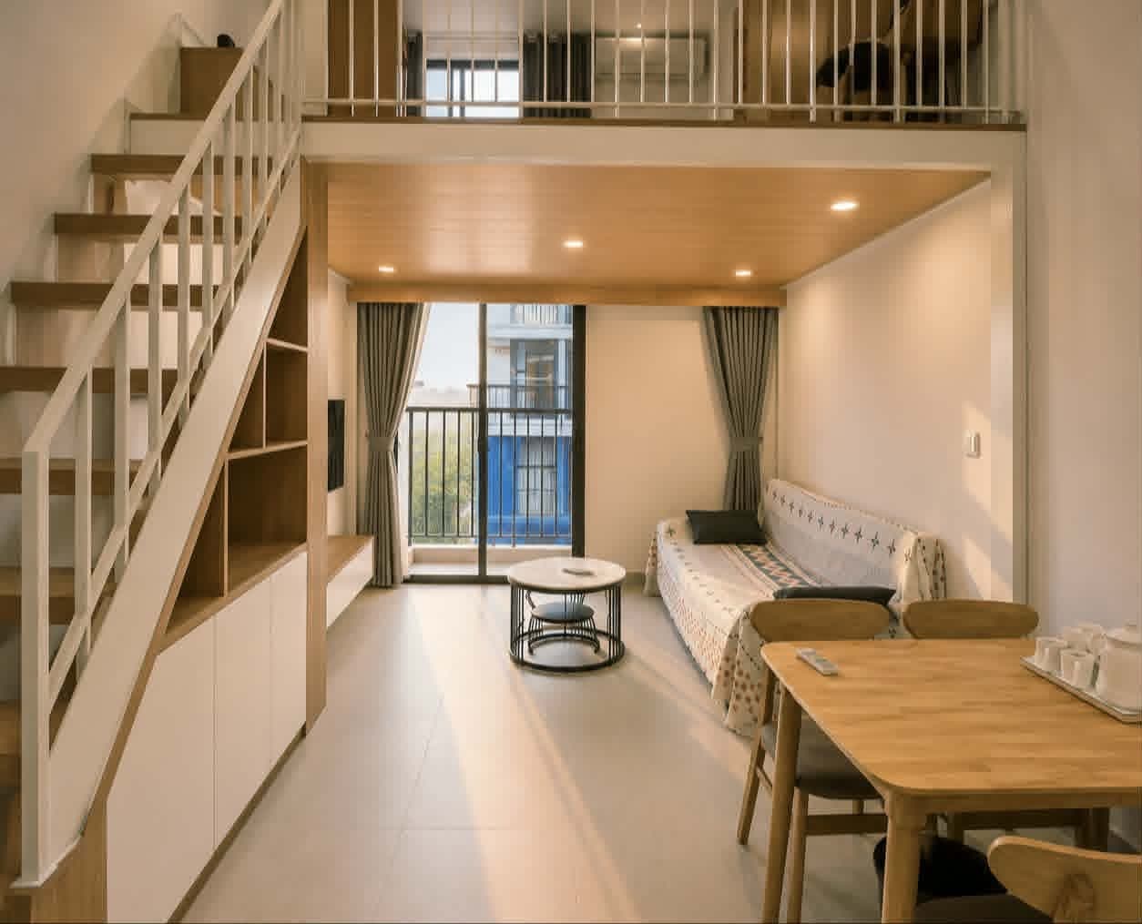A607 — Toàn cảnh studio gác lửng với cầu thang gỗ, kệ sách âm tường và khu khách