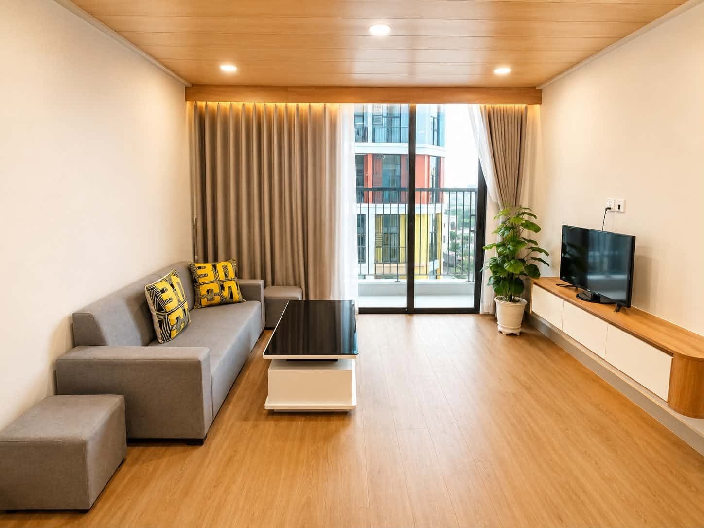 A403A-2 — Phòng khách sofa xám, smart TV và ban công kính rộng